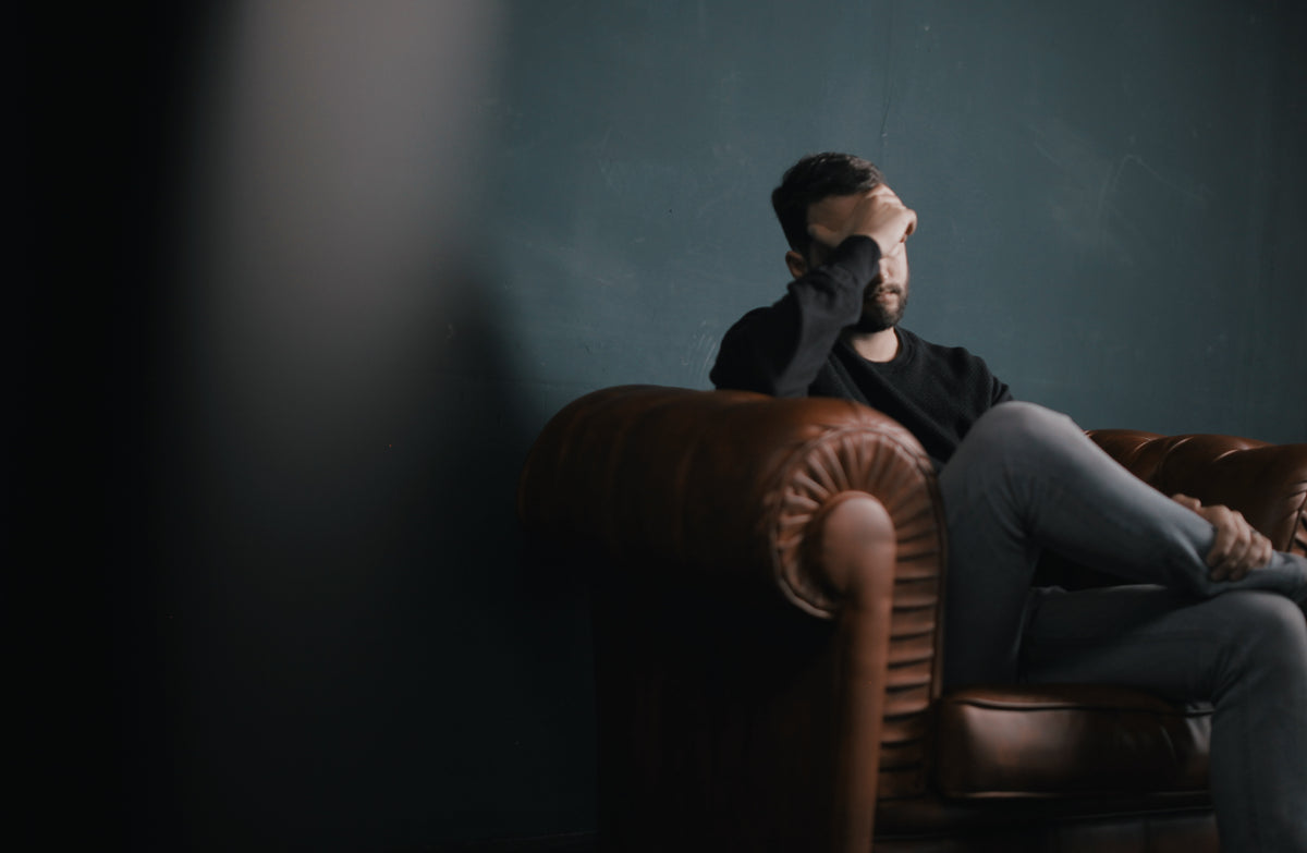 Man with a headache seating on a sofa